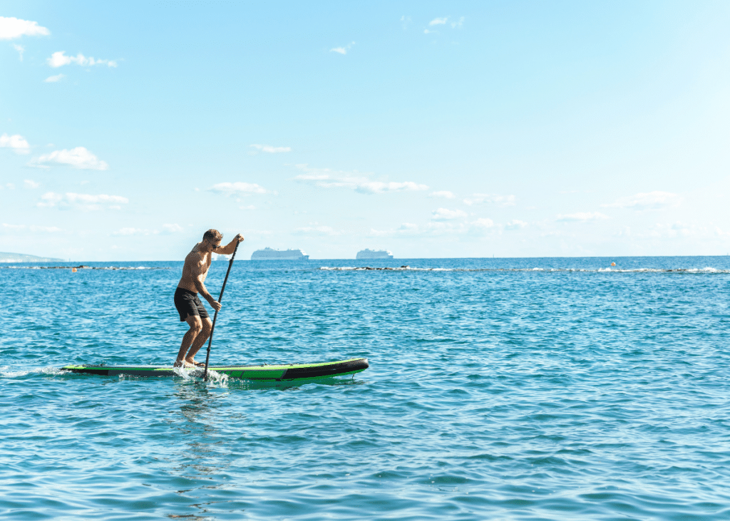 adult male stand up paddleboarding on open water