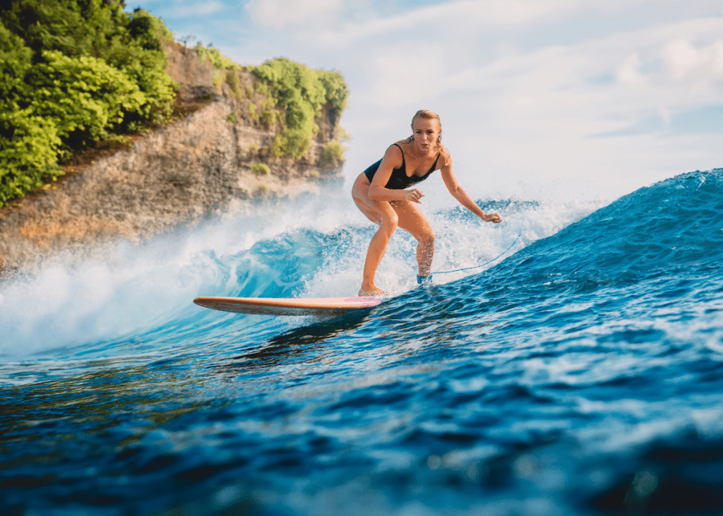 young woman surfing on a wave on an orange surfboard