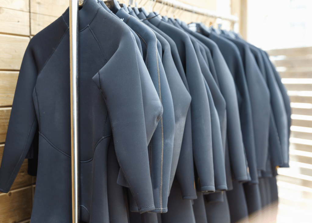 rack of black wetsuits hanging to dry