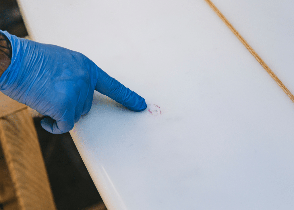 surfer identifying ding while cleaning surfboard