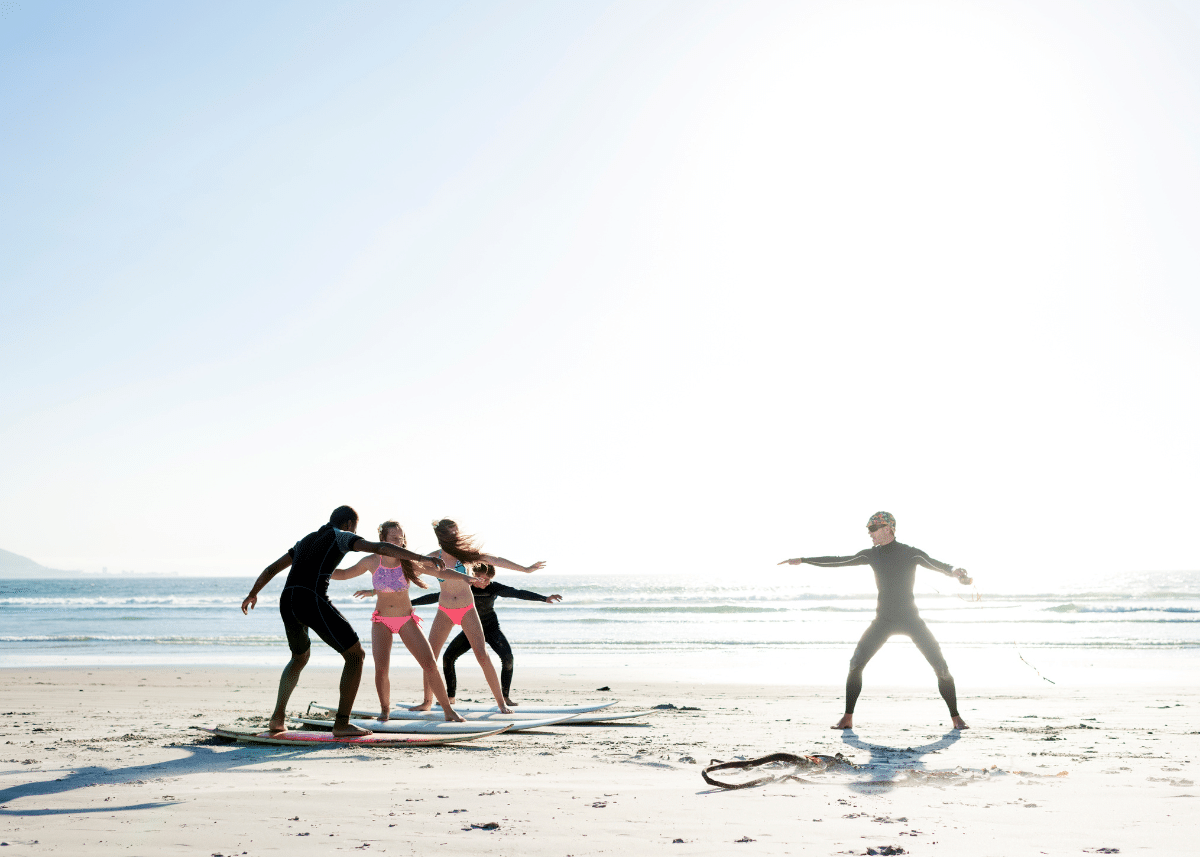 surf instructor demonstrating how to stand on a surfboard during a surfing lesson