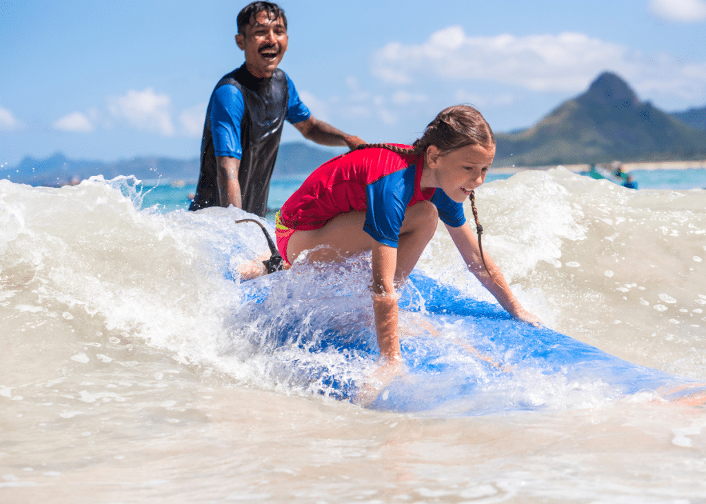 surfing instructor showing a child how to surf during a surfing lesson