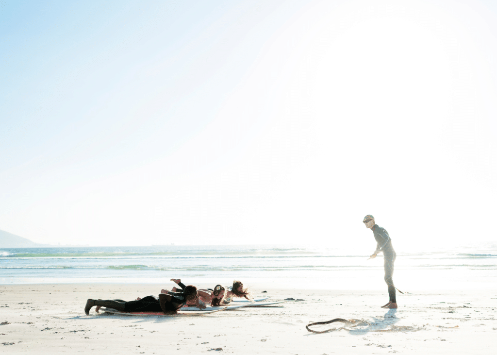 surfing instructor demonstrating how to paddle on a surfboard during a surfing lesson