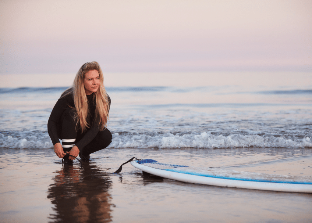 surfer adjusting her leash to prevent surfer rash
