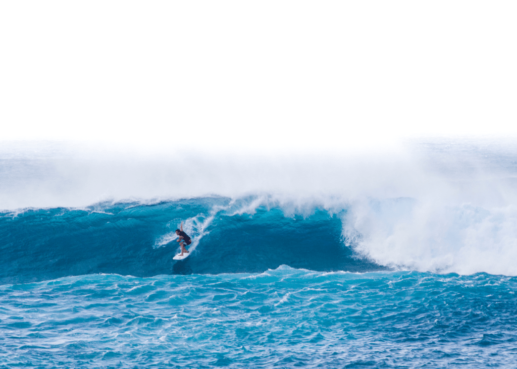 A surfer rides a large, vibrant blue wave at the best tide for surfing in a vast ocean, with mist spraying from the wave's crest.