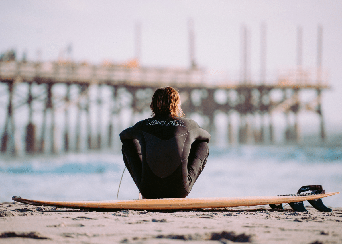 a surfer sitting on a surfboard while looking out into the ocean
